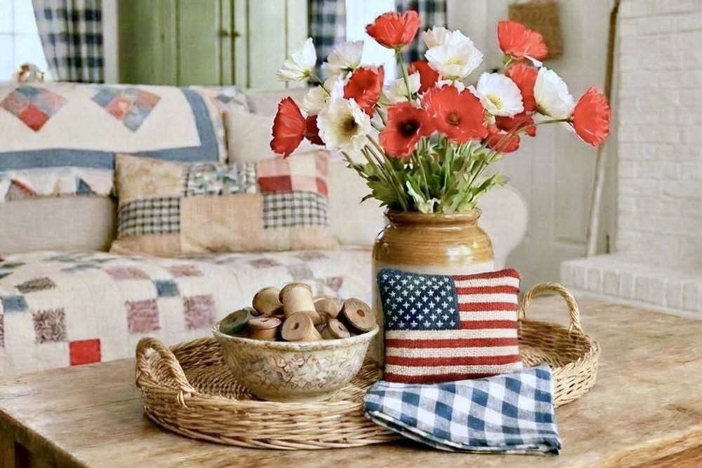 Collected coffee table vignette with red and white poppies, a woven tray, and a patchwork quilt sofa, styled in layered groupings