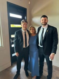 Tracy with her two grown sons, dressed up for a special occasion